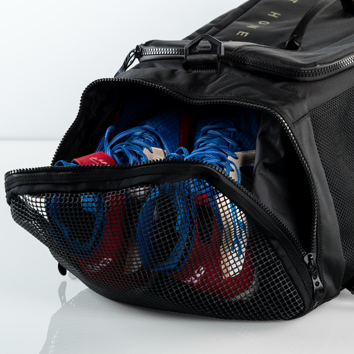 ONX Black duffel bag with blue and red sneakers inside on a white background